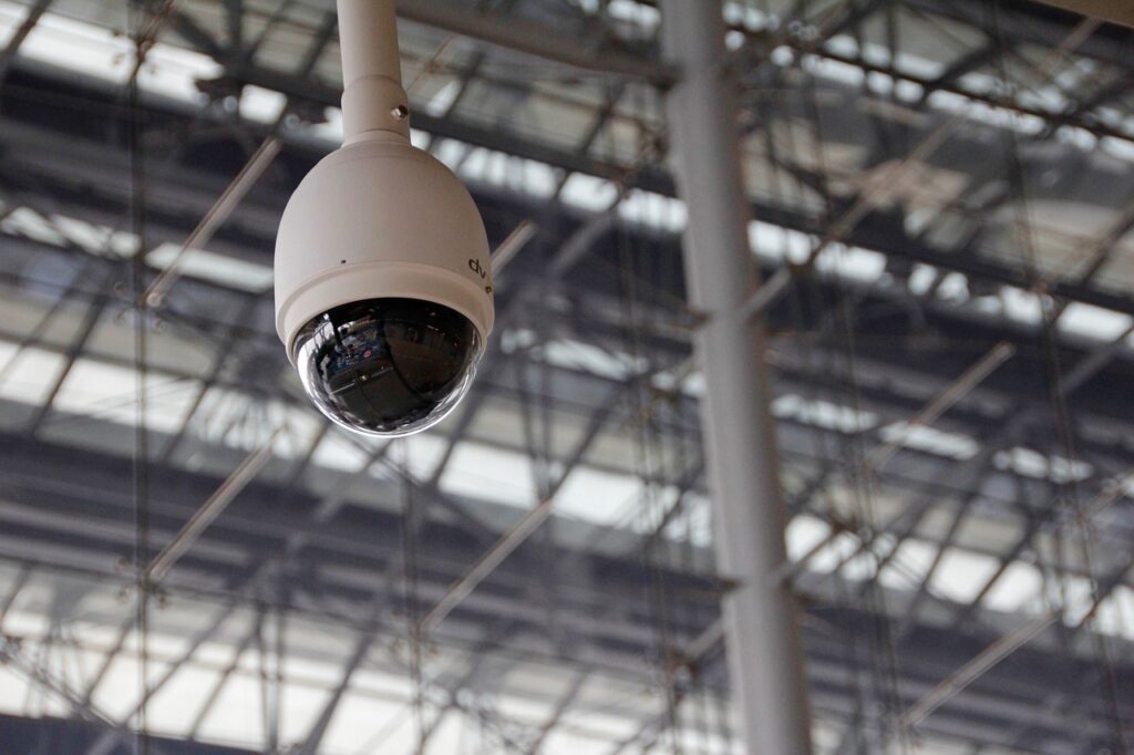 Überwachungskamera in einer Halle, die zur Überwachung und Sicherheit sorgt und die Einhaltung von IT-Sicherheitsrichtlinien gewährleistet.
