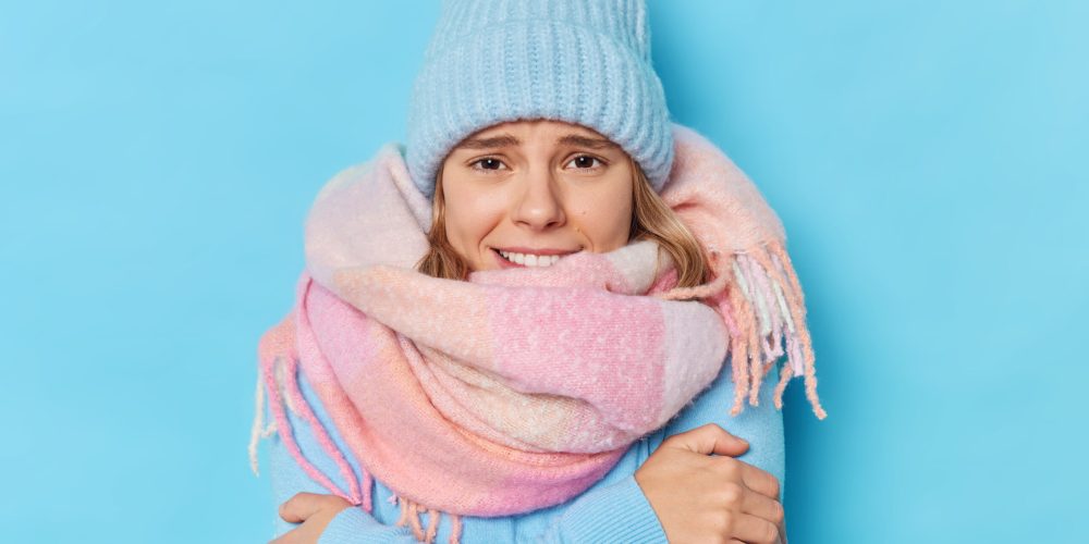 Junge Frau eingepackt in Winterklamotten friert